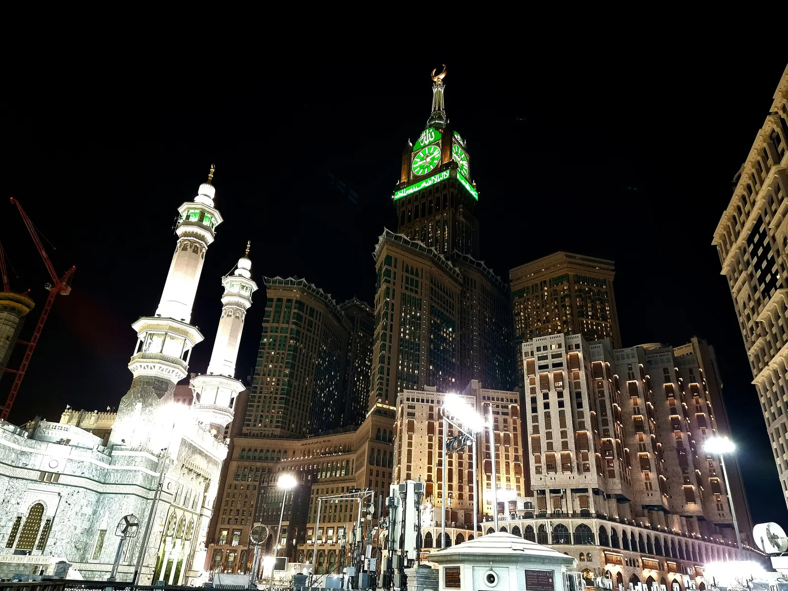 Gates and minarets of Masjid al-Haram lit at night beneath the illuminated Makkah Clock Tower