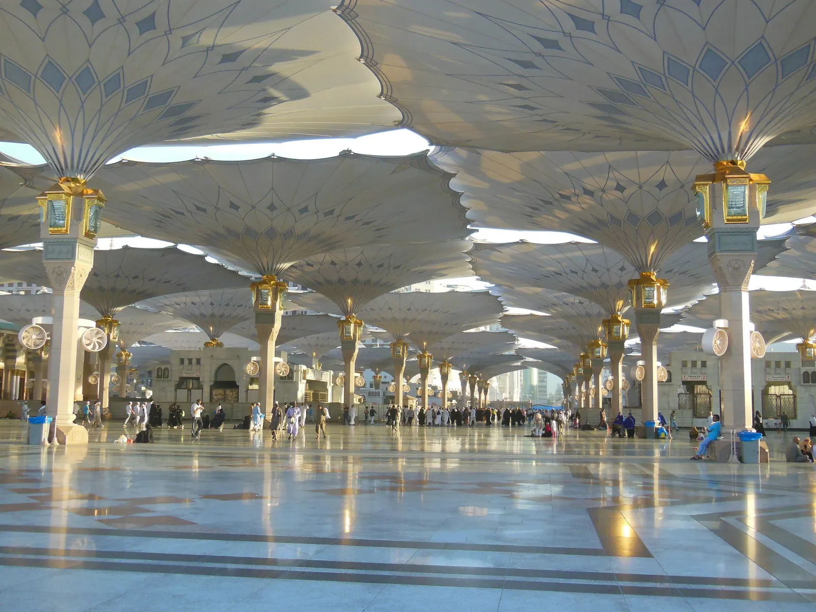 Open shade umbrellas over the marble courtyard of Masjid an-Nabawi in early morning light